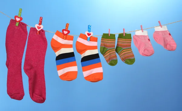 Colorful socks hanging on clothesline, on color background — Stock Photo, Image
