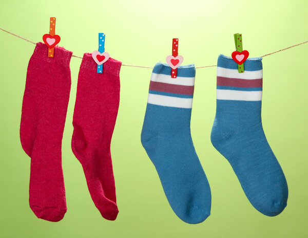 Colorful socks hanging on clothesline, on color background