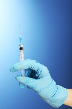 Doktor holding şırınga ile mavi arka plan üzerinde bir aşı