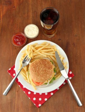 patates kızartması ve ahşap zemin üzerinde soğuk içecek ile lezzetli peynirli burger