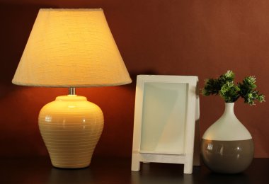 beyaz fotoğraf çerçevesi ve kahverengi duvar zemin üzerine ahşap masa lambası