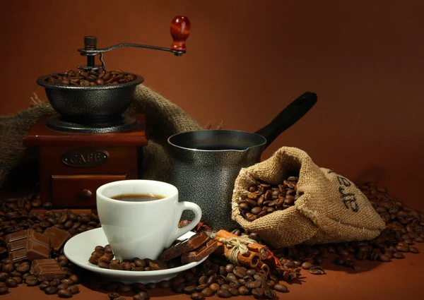Kopje koffie, grinder, turk en koffie bonen op bruine achtergrond — Stockfoto