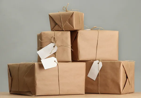 Cajas de paquetes con papel kraft, sobre mesa de madera sobre fondo gris — Foto de Stock