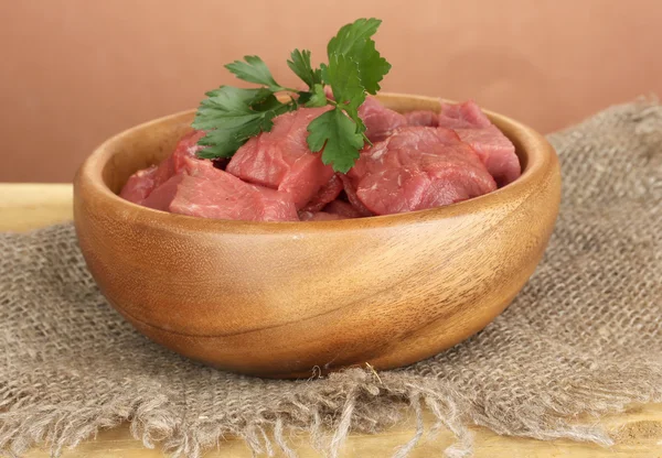 Raw beef meat in bowl on wooden table on brown background — Stock Photo, Image
