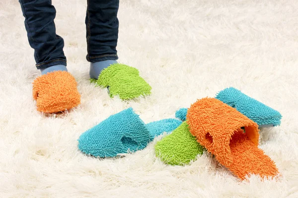 Female legs in color slippers, on carpet background — Stock Photo, Image