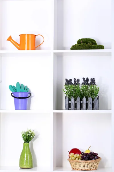 Hermosas estanterías blancas con diferentes objetos relacionados con la jardinería — Foto de Stock