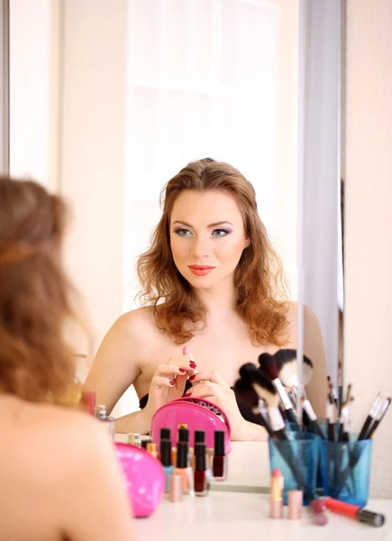 Молодая красивая женщина делает макияж возле зеркала — стоковое фото