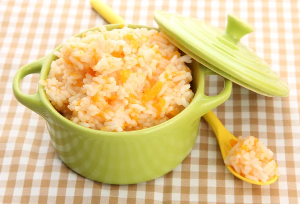 Taste rice porridge with pumpkin in saucepan on tablecloth background — Stock Photo, Image