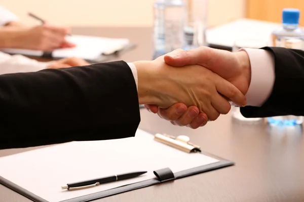 Negocios estrechando las manos, en el fondo de la oficina — Foto de Stock