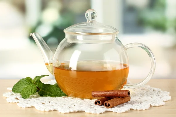 Teapot with mint and cinnamon on table in room — Stock Photo, Image