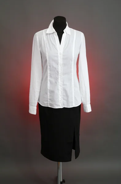 Białą bluzkę i czarną spódnicę z herbu na manekin na kolor tła — Zdjęcie stockowe