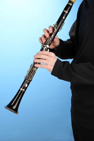 Музикант грає на кларнеті на синьому фоні — стокове фото
