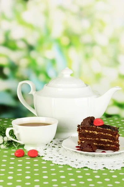 Teapot, cup of tea and delicious cake on natural background — Stock Photo, Image