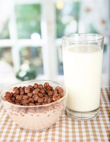 Delicious and healthy cereal in bowl with milk on table in room — Stock Photo, Image