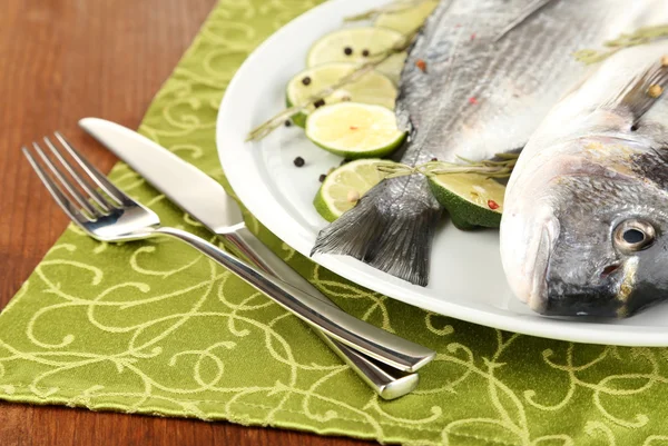 Two fish dorado with lemon on plate on wooden table close-up — Stock Photo, Image