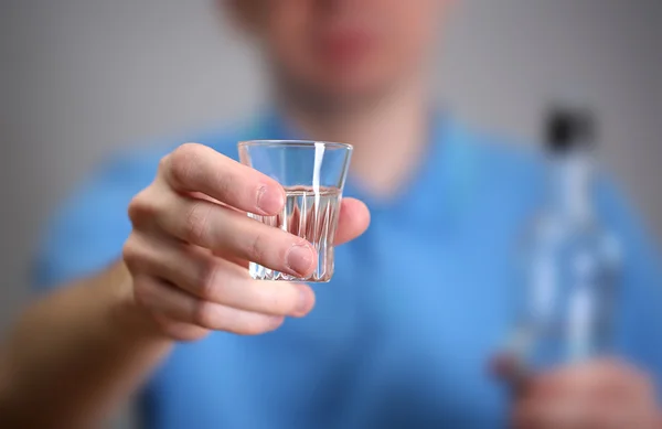 Muž se sklem alkoholu na šedém pozadí — Stock fotografie