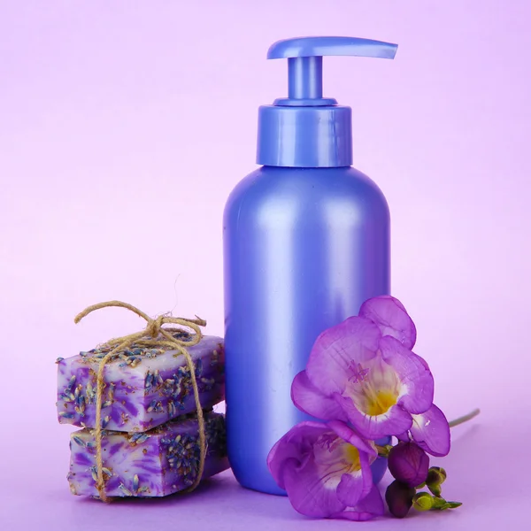 Płyn i ręcznie robione mydła na fioletowym tle — Zdjęcie stockowe