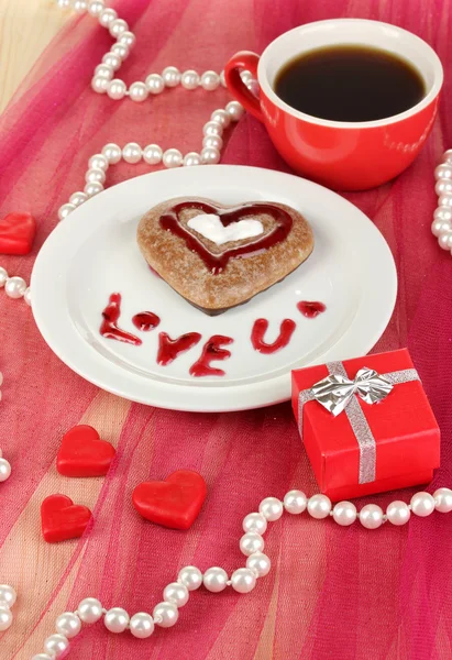 Chocolade cookie in vorm van hart met kopje koffie op roze tafellaken close-up — Stockfoto