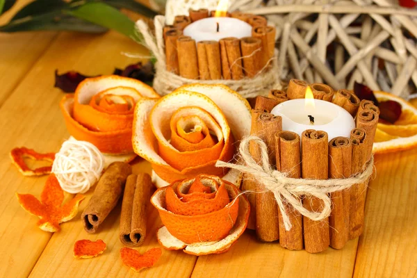 Decorative rose from dry orange peel and burning candles on wooden table — Stock Photo, Image