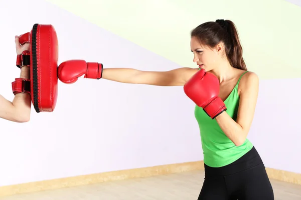 Mujer hermosa joven con guantes de boxeo en el entrenamiento, en el gimnasio —  Fotos de Stock