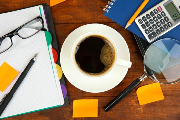 Tasse de café sur la table de travail recouverte de documents close up — Photo