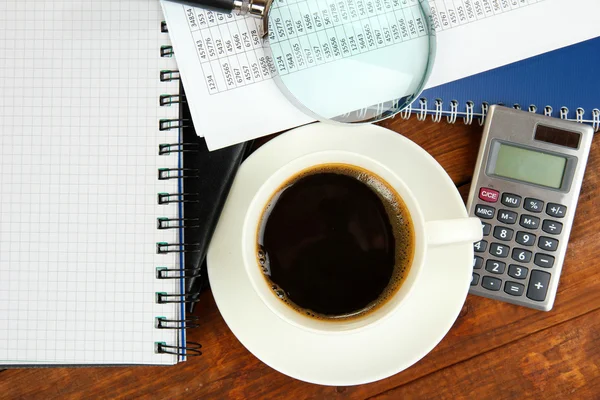 Tasse de café sur la table de travail recouverte de documents close up — Photo