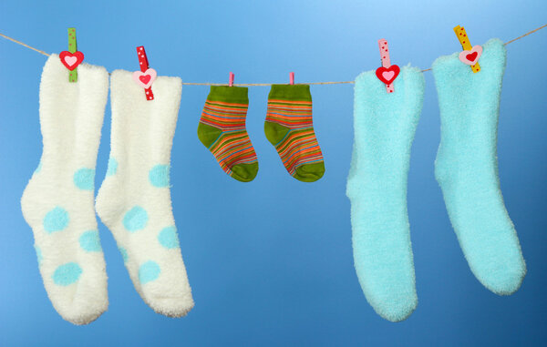 Colorful socks hanging on clothesline, on color background