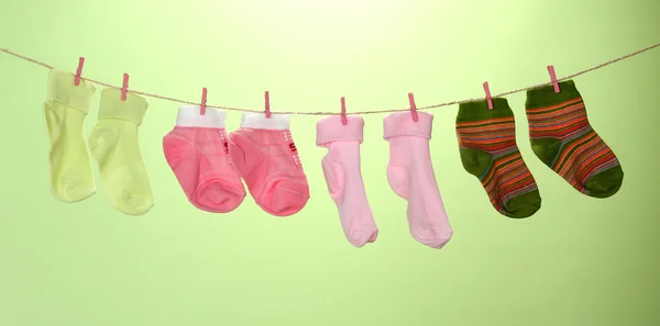Colorful socks hanging on clothesline, on color background — Stock Photo, Image