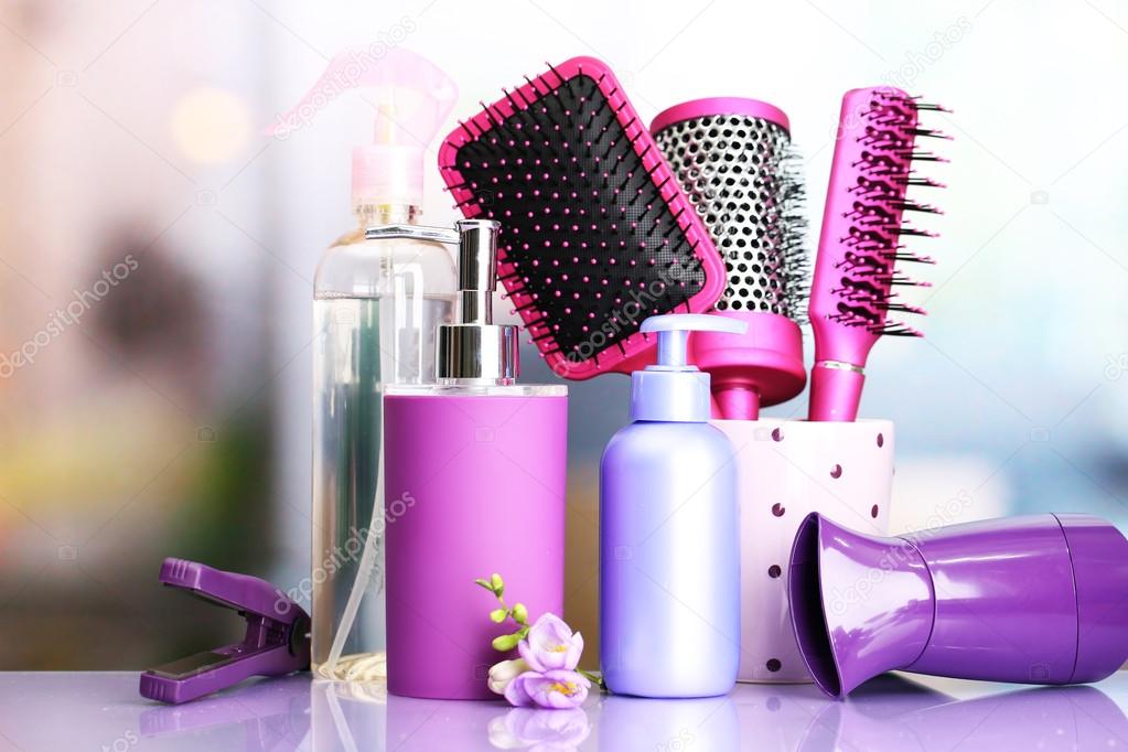 Hair brushes, hairdryer, straighteners and cosmetic bottles in beauty salon