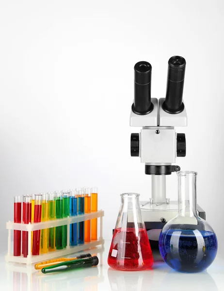 Test tubes with colorful liquids and microscope isolated on white — Stock Photo, Image