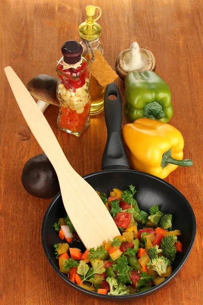 Sliced fresh vegetables in pan with spices and ingredients on wooden table — Stock Photo, Image