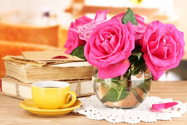 Belles roses roses dans un vase sur une table en bois sur fond de pièce — Photo