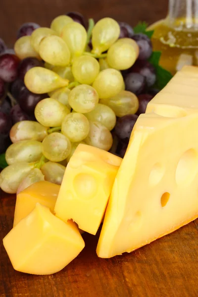 Cut cheese with grape on wooden table — Stock Photo, Image