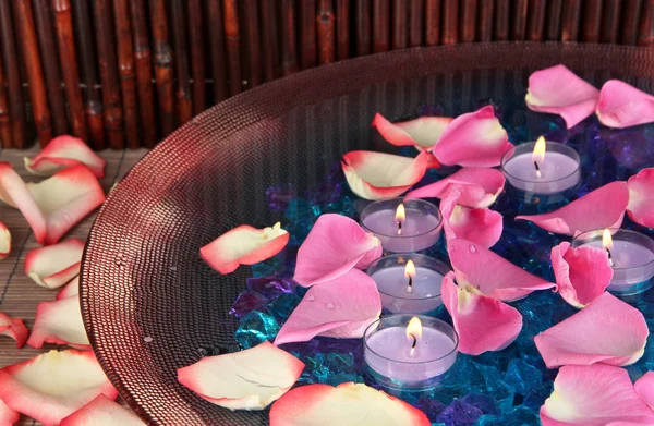 Rosenblätter und Kerzen in Wasser in Vase auf Holztisch auf Holzgrund — Stockfoto