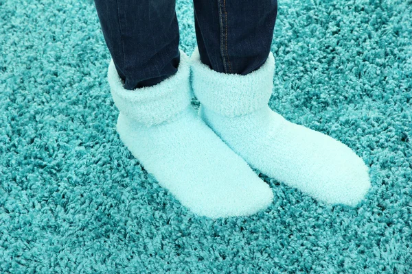 Patas femeninas en calcetines de colores sobre fondo de alfombra de color — Foto de Stock
