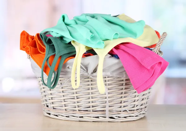 Clothes in wooden basket on table in room — Stock Photo, Image