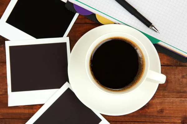 Cup of coffee on worktable covered with photo frames close up — Stock Photo, Image