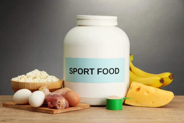 Barattolo di proteine in polvere e cibo con proteine, su fondo grigio — Foto Stock