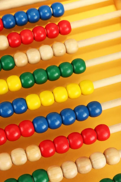 Abacus de brinquedo de madeira brilhante, no fundo amarelo — Fotografia de Stock