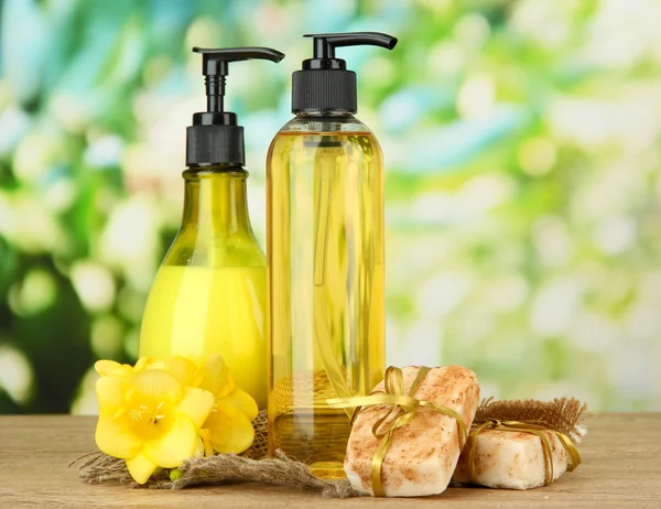 Liquid and hand-made soaps on wooden table, on green background — Stock Photo, Image