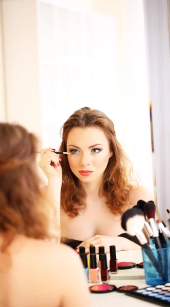 Jong mooi vrouw maken make-up in de buurt spiegel — Stockfoto