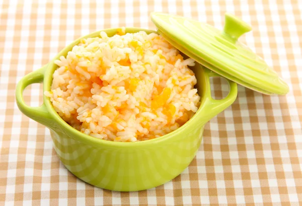 Taste rice porridge with pumpkin in saucepan on tablecloth background — Stock Photo, Image