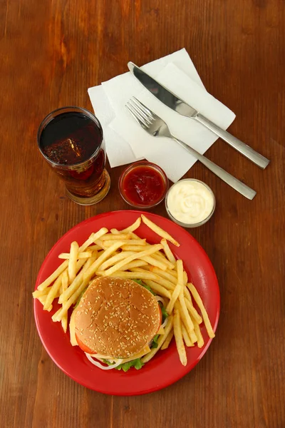 Tasty cheeseburger with fried potatoes and cold drink, on wooden background — Stock Photo, Image