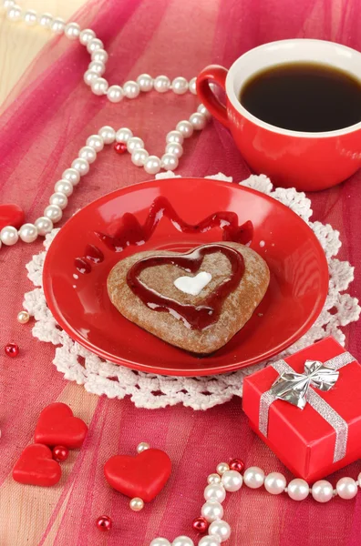 Galleta de chocolate en forma de corazón con taza de café en mantel rosa de cerca —  Fotos de Stock