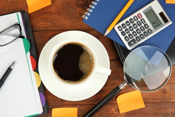 Tasse de café sur la table de travail recouverte de documents close up — Photo