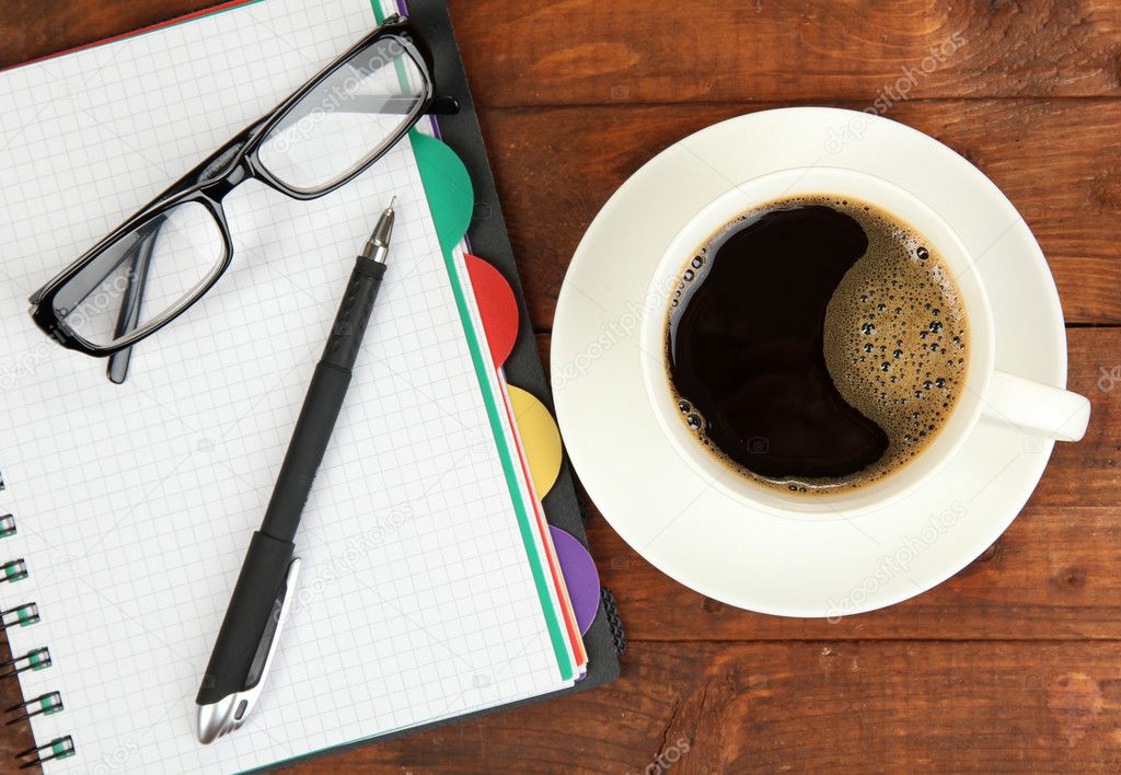 Cup of coffee on worktable covered with documents close up