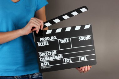 Film üretim clapper panosundaki gri arka plan üzerinde eller