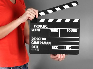 Film üretim clapper panosundaki gri arka plan üzerinde eller