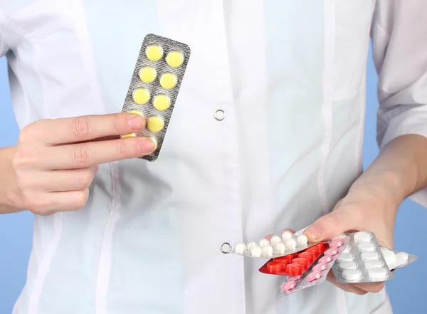 Close-up of female doctor hand holding pills, on color background — Stock Photo, Image