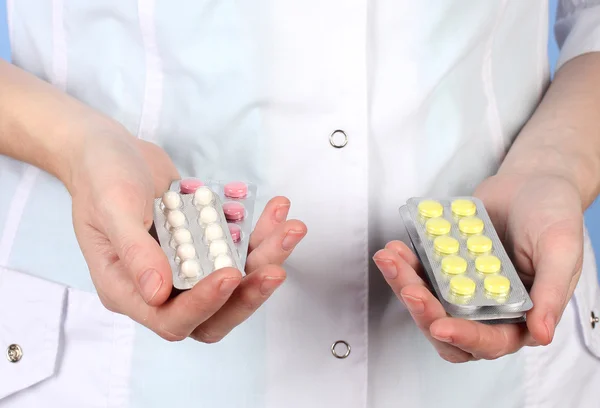 Close-up of female doctor hand holding pills, on color background — Stock Photo, Image